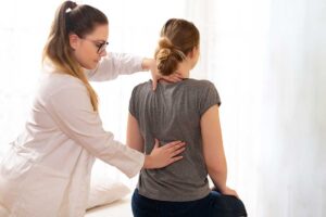 A person in casual clothing receiving a gentle chiropractic adjustment in a bright, professional office.