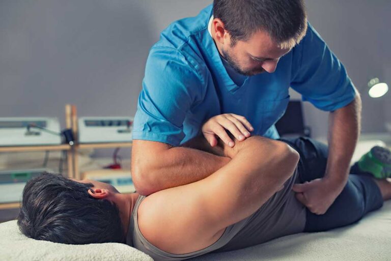 Adult performing gentle shoulder mobility exercises beside a sturdy chair in a bright living room.
