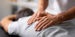 Pregnant woman doing gentle stretching on a mat beside a supportive pillow and warm compress.